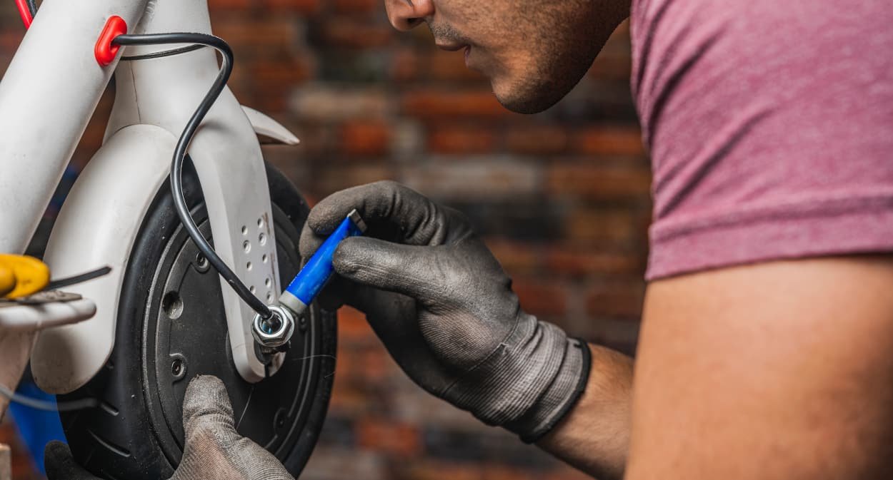 Close up of a hispanic mechanic male holding a wheel rim of an electric scotter for repair